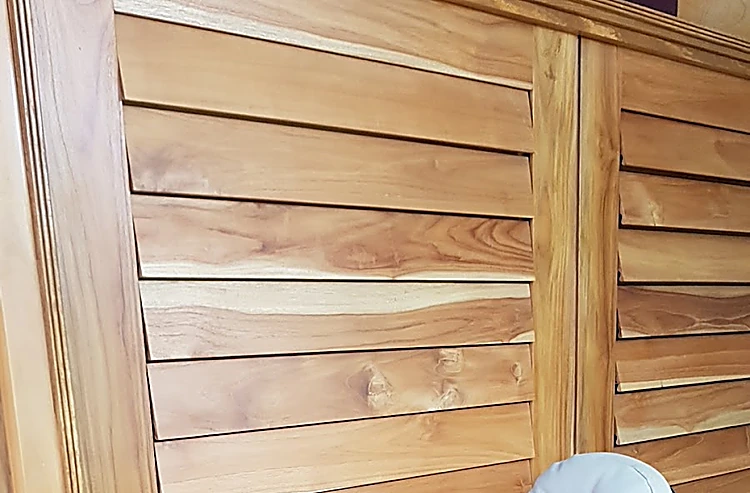 Detalle de la persiana de teca de la recepción, con sus listones inclinados y la veta de la madera